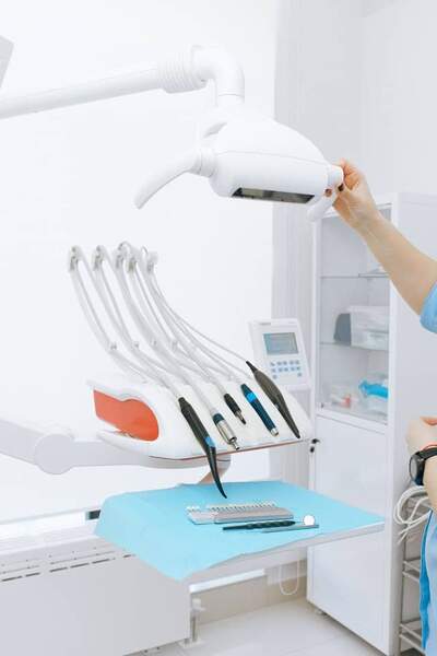 Photograph of dentist adjusting light over an examination chair with dental tools laid out